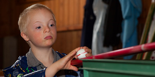 Un jeune garçon, intéressé et attentif, observe une table de billard.