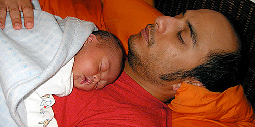 Un papa fait la sieste avec son bebe sur la poitrine