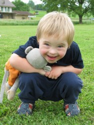 un jeune garçon curieux accroupi, son singe-doudou sous le bras