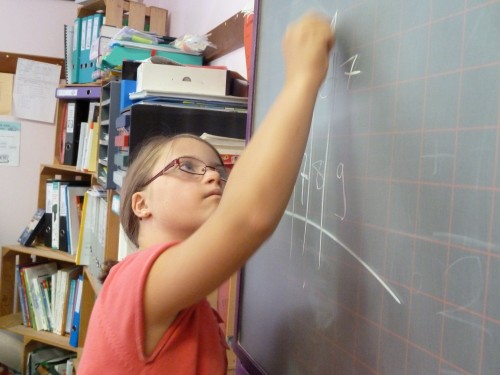 une fillette fait un calcul au tableau noir